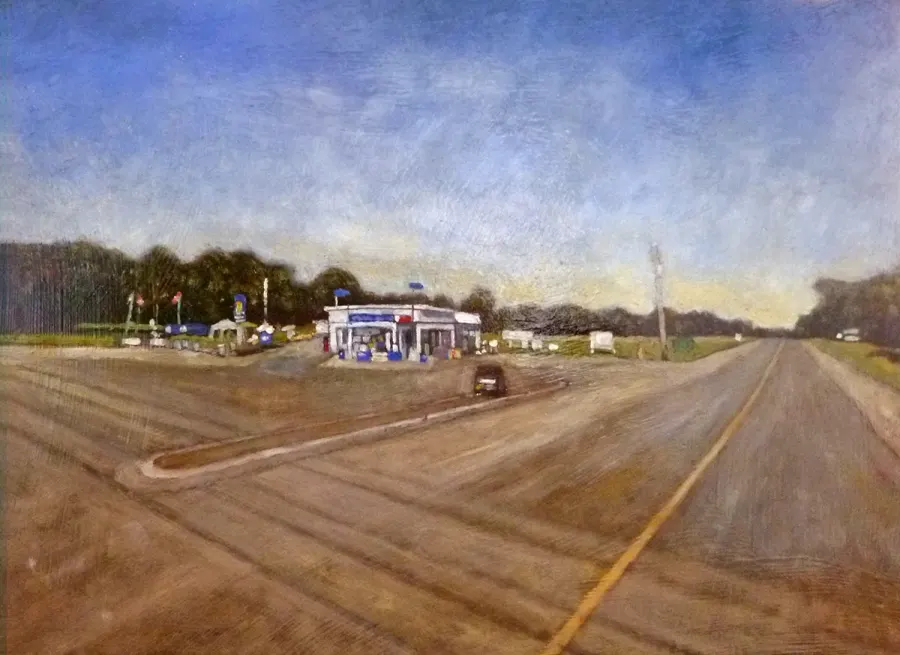 A roadside gas station under a wide blue sky, with the road running off into the distance